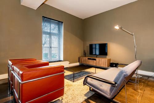 a living room with a chair and a television at Landgoed Kasteel de Hoogenweerth in Maastricht