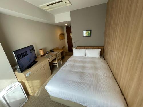 a hotel room with a bed and a tv at QuintessaHotel TokyoHaneda Comic&Books in Tokyo
