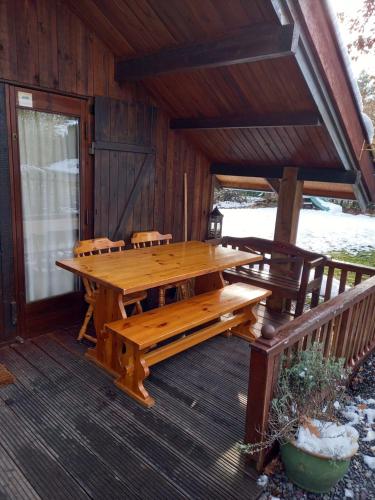 a wooden table and benches on a porch of a cabin at fraai chalet Barvaux in Durbuy