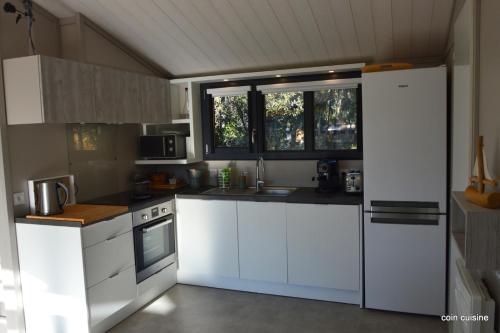 uma cozinha com armários brancos e um frigorífico branco em Chalet la lande em Ondres