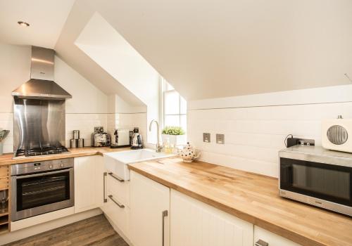 a kitchen with white cabinets and wooden counter tops at Hideaway in North Berwick