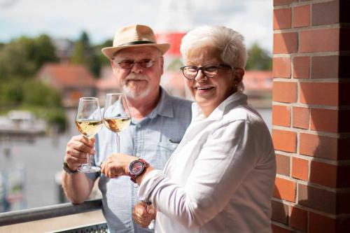 an older man and woman holding glasses of white wine at Hafen-Apartment Aurich in Aurich
