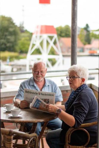 an older man and woman sitting at a table with a book at Hafenapartments-Aurich in Aurich