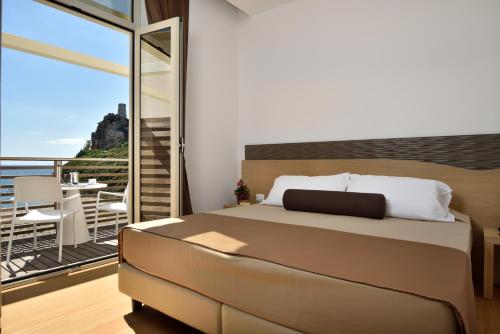 1 Schlafzimmer mit einem Bett und einem Balkon mit einem Tisch in der Unterkunft Hotel Club Torre Salinas - Adults Only in Muravera