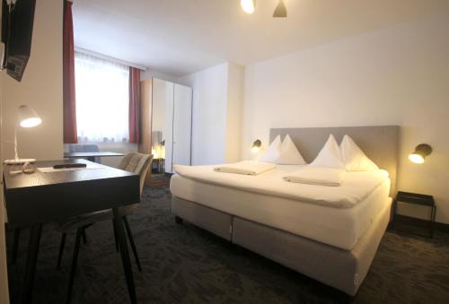 ウィーンにあるホテル アルトマンのベッドとデスクが備わるホテルルームです。