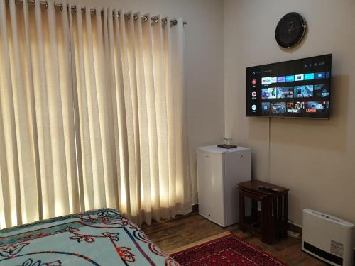 a room with a television and a bed and a refrigerator at Alpha Guest House in Rawalpindi