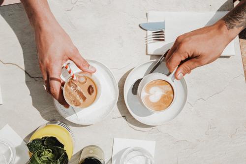 a person holding a cup of coffee on a table at QC Hotel Quartier Chiemsee in Seebruck