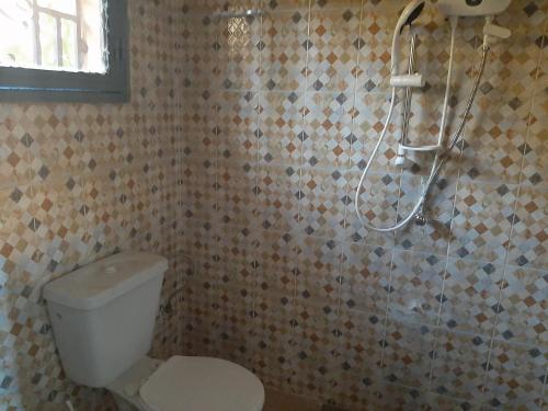 y baño con ducha, aseo y cabezal de ducha. en Villa Chambre A climatisée douche Cuisine salon, en Bamako