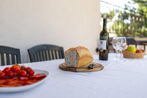 a table with a plate of bread and a bottle of wine at Seaside Guesthouse by JR City Apartments in Jadranovo