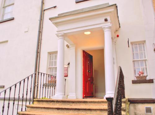 una puerta roja en una casa blanca con escaleras en Morehampton Townhouse, en Dublín