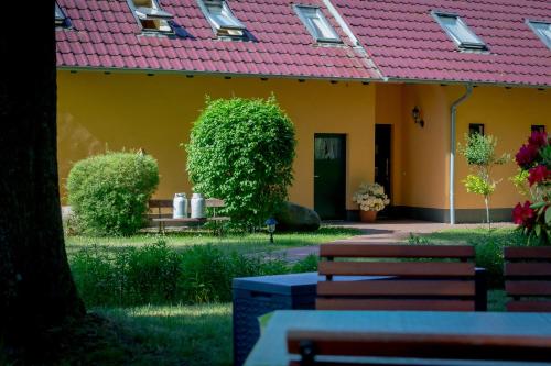 a yellow building with a pink roof and benches at Matys Landhausperle an der Müritz in Röbel