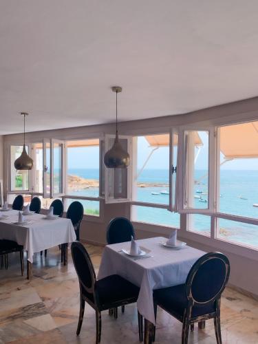 a restaurant with tables and chairs with a view of the ocean at Hotel Patricia in Torreguadiaro