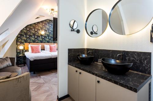 a bathroom with two sinks and a bedroom at Boutique Hotel Rijks I Kloeg Collection in Goes