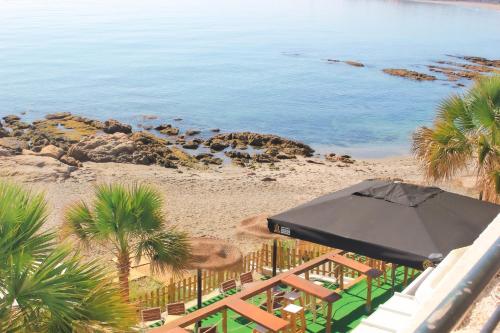a balcony with an umbrella and a beach at Hotel Patricia in Torreguadiaro