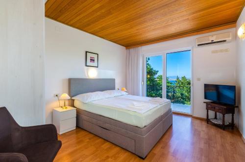 sypialnia z łóżkiem, telewizorem i kanapą w obiekcie Seaside Guesthouse by JR City Apartments w mieście Jadranovo