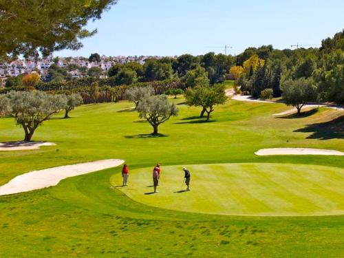 dos personas jugando golf en un campo de golf en Flamenca Village by Mar Holidays, en Orihuela