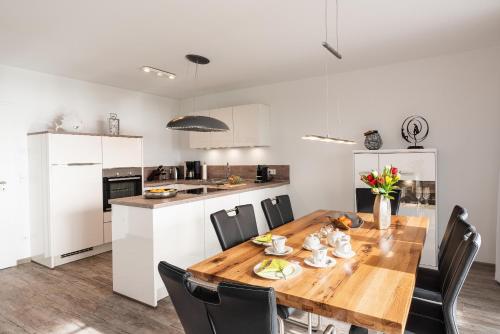 a kitchen and dining room with a wooden table and chairs at Terrassenwohnung "Kliffgarten" - Oase am Haff in Garz-Usedom