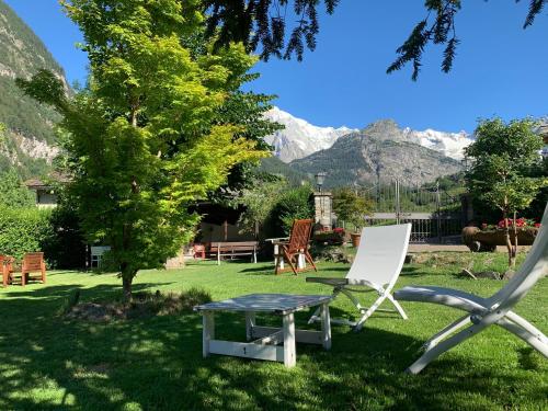 a chair and a table in a yard with mountains at Hameau De Jadis in Pré-Saint-Didier