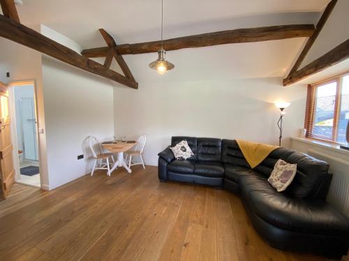 a living room with a black leather couch and a table at Smithy Cottage in Berriew