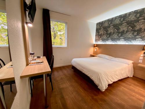 a bedroom with a bed and a desk and a window at Hotel de Bordeaux in Toulouse