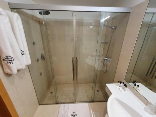 a shower with a glass door next to a sink at Hotel Dunas d'Ovar in Ovar