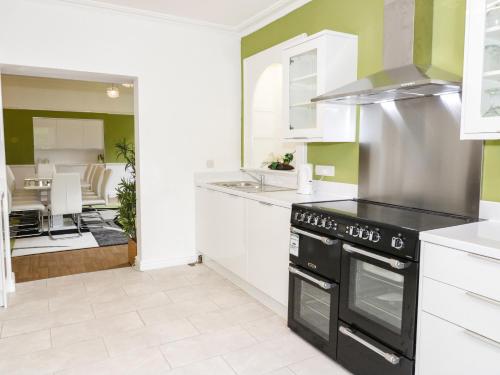 a kitchen with white cabinets and a black stove top oven at Plas Coch in St Asaph