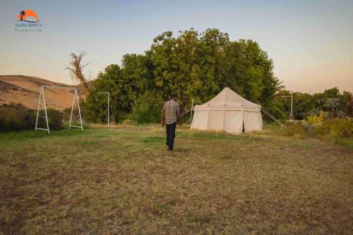 a man walking in a field next to a tent at Nuba Narty in Aswan