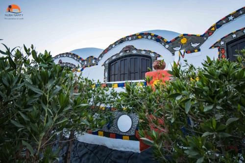 a building with a fence with trees in front of it at Nuba Narty in Aswan