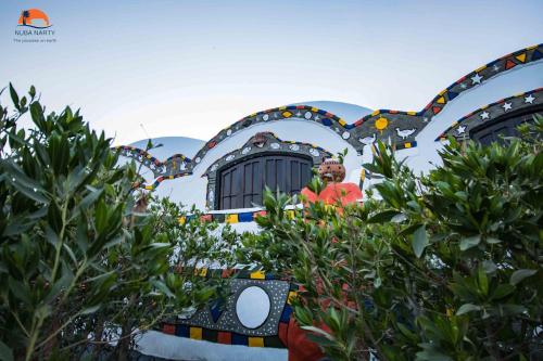 a man standing in front of a building with trees at Nuba Narty in Aswan