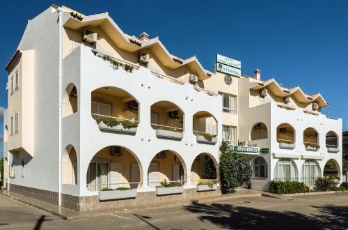 a large white building with balconies on a street at Hotel Apartamento A Floresta do Jose in Almancil