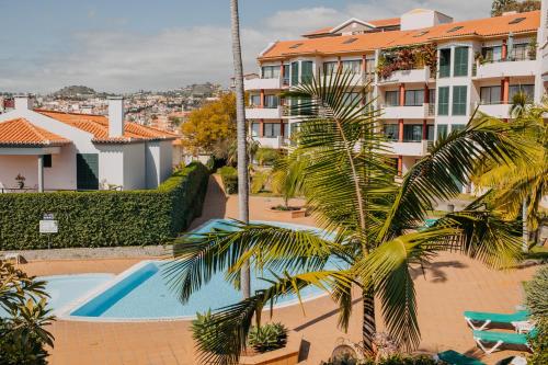 a palm tree in front of a building with a swimming pool at Funchal Lounge Apartment by Amazing Madeira in Funchal