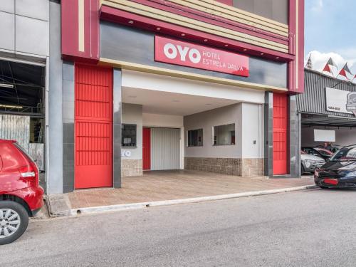 una tienda con puertas rojas y un coche aparcado fuera en OYO Estrela Dalva, São Paulo, en São Paulo