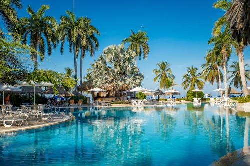 a beach with palm trees and palm trees at Zuana Beach Resort in Santa Marta