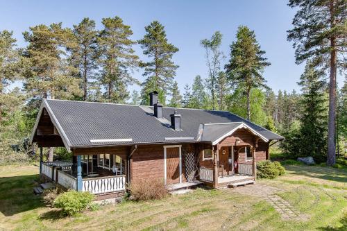 una casa di tronchi con tetto di paglia e portico di Tyngsjö Vildmark a Tyngsjö