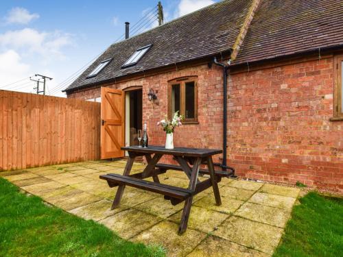 a picnic table in front of a brick house at Combine Shed in Bidford