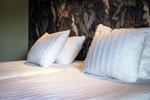 a bed with white pillows on top of it at Hotel het Anker van Texel in De Cocksdorp