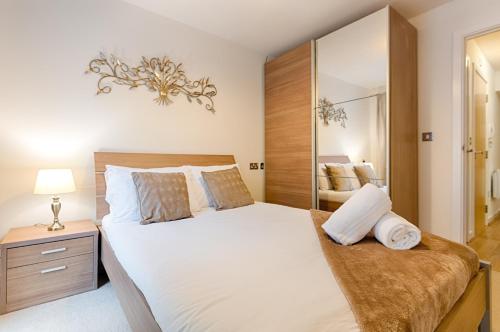 een slaapkamer met een groot wit bed en een spiegel bij Royal Sovereign with Parking - TV in every Bedroom! in Swansea