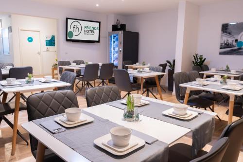 a dining room with tables and chairs and a tv at Friends Hotel Bad Salzuflen in Bad Salzuflen