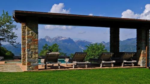 a group of chairs and a pool with mountains in the background at L'Ormasso in Pieve Fosciana