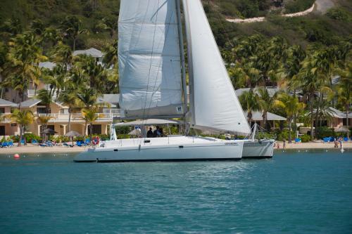 a sailboat on the water next to a beach at St. James's Club Resort - All Inclusive in English Harbour Town