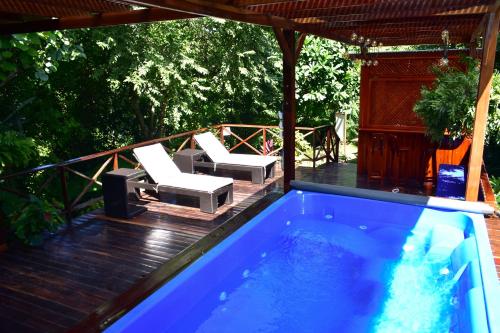 a swimming pool on a deck with two chairs and a table at Ecohotel Yachay Tayrona in El Zaino