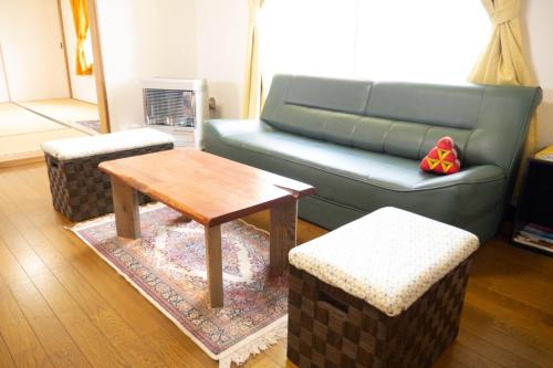 un soggiorno con divano blu e tavolo di Maeda Forestry House - Vacation STAY 19585v a Furano