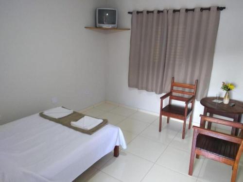 ein Schlafzimmer mit einem Bett, einem Stuhl und einem Tisch in der Unterkunft Pousada Sol de Minas in Monte Sião