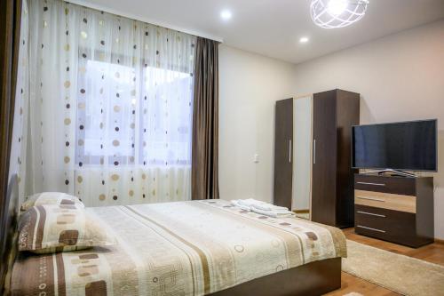 a bedroom with a bed and a flat screen tv at Guest House Angelkovi in Sapareva Banya