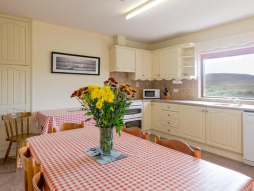 a kitchen with a table with a vase of flowers on it at Beachmount House in Ventry