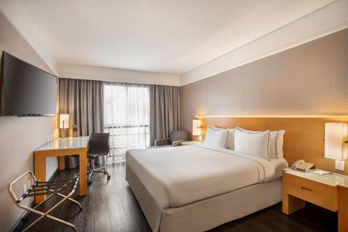 een hotelkamer met een groot bed en een bureau bij Meliá Campinas in Campinas