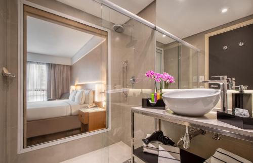 a bathroom with a sink and a glass shower at Meliá Campinas in Campinas