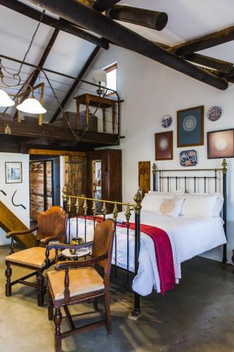 a bedroom with a large bed and two chairs at Schaftplaas Cottages in Langebaanweg