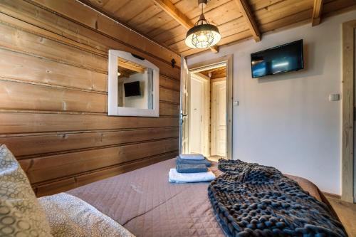 a bedroom with a bed in a room with wooden walls at Willa w Ubocy - "Jacuzzi i Sauna w ofercie dodatkowo płatnej" in Murzasichle