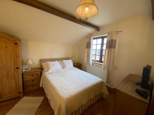 a bedroom with a white bed and a window at Thompsons Arms Cottages in Flaxton